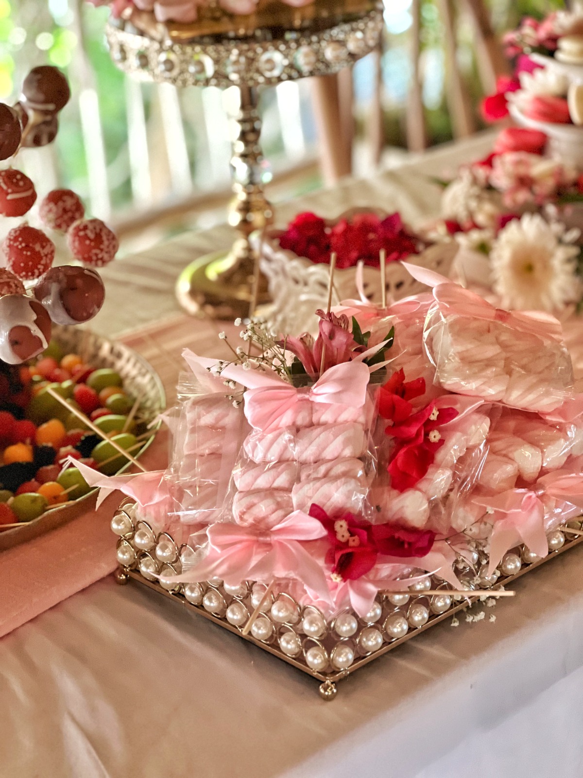 Styled birthday dessert table with sweets wrapped in pink ribbon
