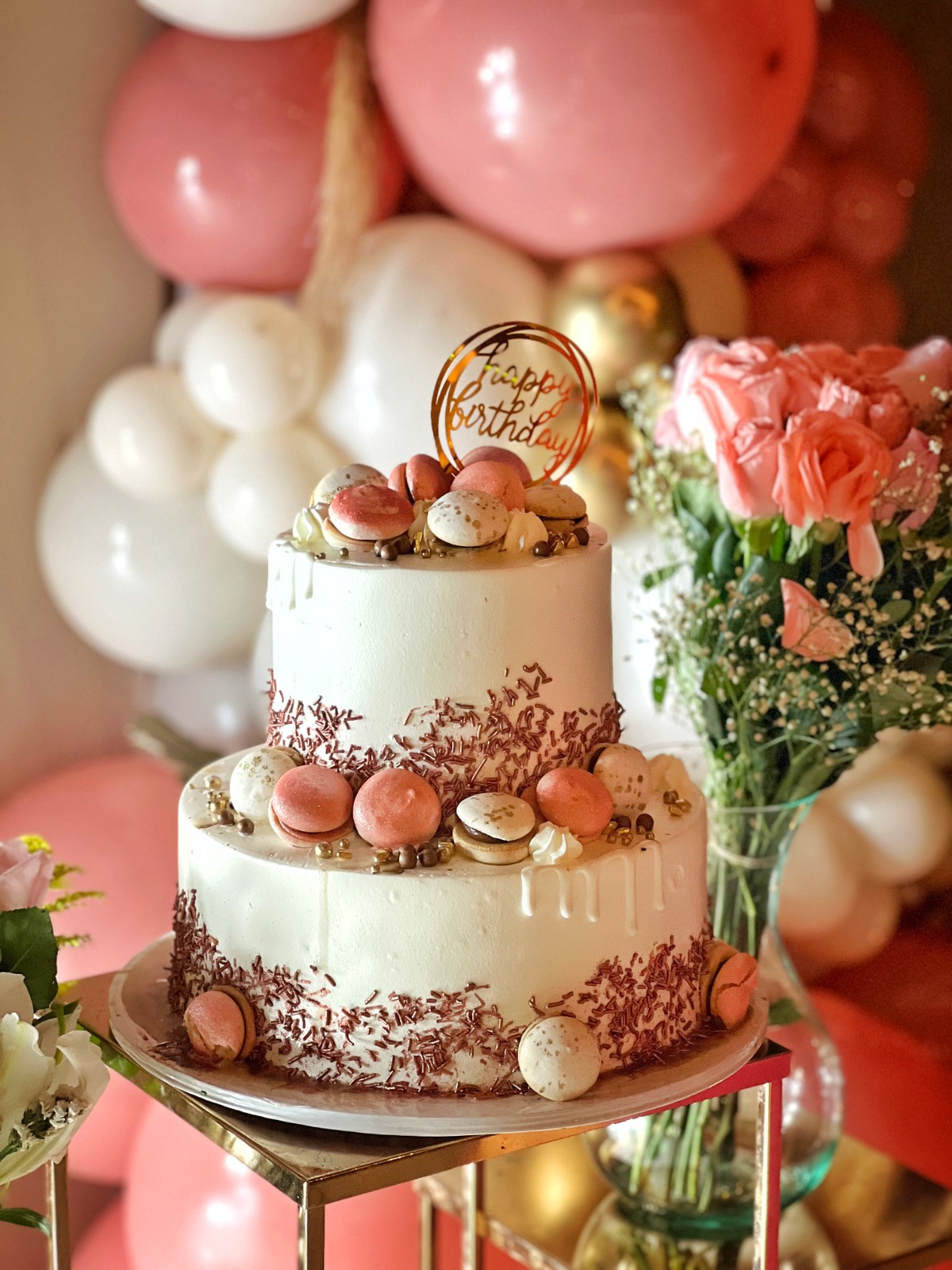 Two-tier birthday cake decorated with macarons and a happy birthday topper
