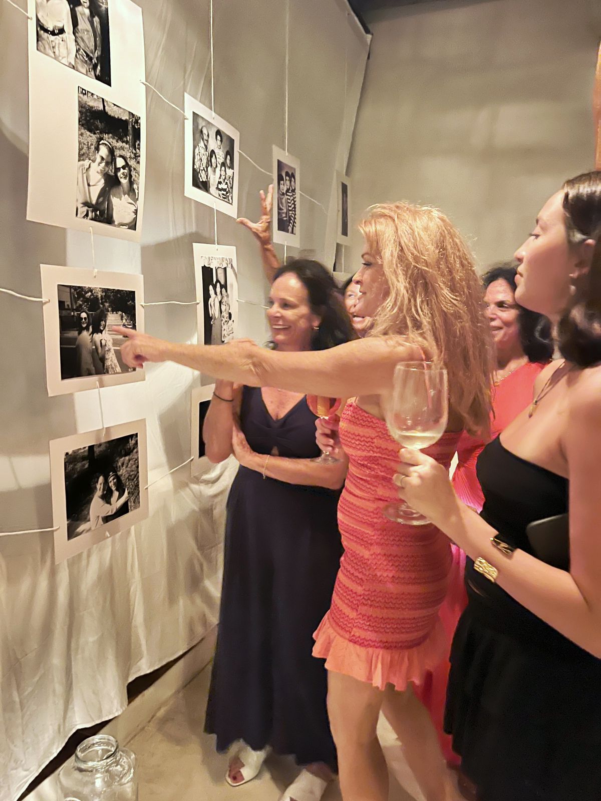 Guests admiring a hanging black and white photo memory wall at a birthday party