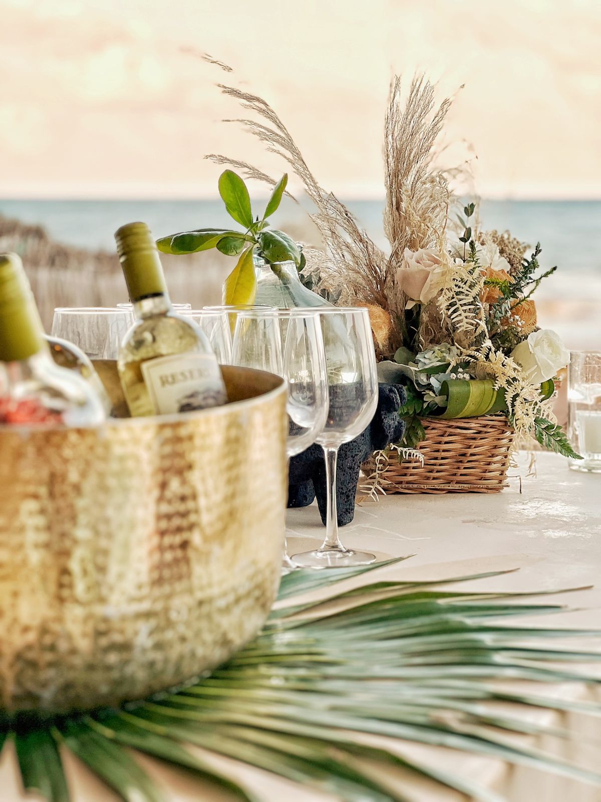 Beachfront table setting with wine and florals at sunset